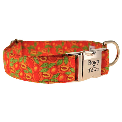 An orange dog collar with peaches and green leaves with gold metal buckle laser engraved with boop town.